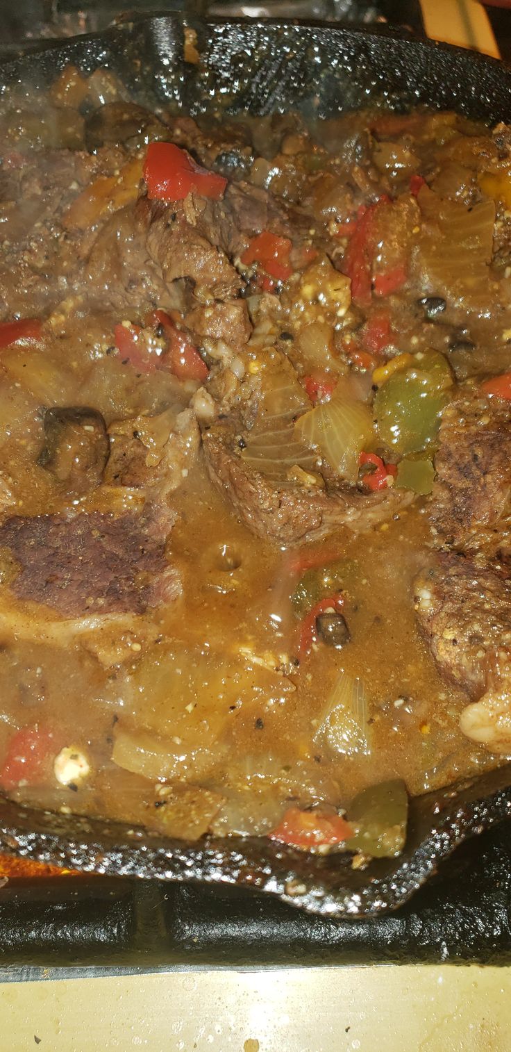 a pan filled with meat and vegetables on top of a stove