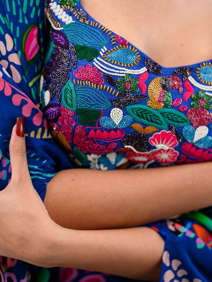 A three-piece Marine Blue Printed Dhoti Skirt Set Paired With Bralette and Cape from the Juhi Bengani collection – Festive 2023. This gorgeous marine blue printed dhoti skirt is paired with a heavy embroidered bralette blouse. The bright and vibrant prints with bird and floral work, heavy embroidery of beads, and thread sequence work enhance this pure crepe dhoti skirt set. This outfit is completed with a marine blue printed cape with embroidered lace border. Blue Silk Blouse Piece With Motifs, Blue Bohemian Georgette Lehenga, Bohemian Blue Georgette Lehenga, Festive Blue Lehenga With Printed Motifs, Blue Bohemian Style Blouse Piece For Festive Occasions, Blue Bohemian Blouse Piece For Festive Occasions, Blue Dress For Navratri, Blue Bollywood Blouse Piece With Motifs, Traditional Blue Blouse With Printed Motifs