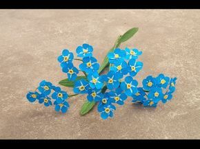 small blue flowers on the ground with green leaves and stems sticking out of it's center