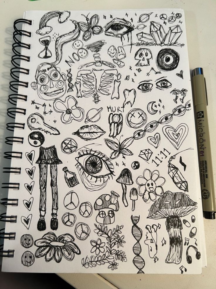 a notebook with drawings on it sitting next to a pen and paper clippings