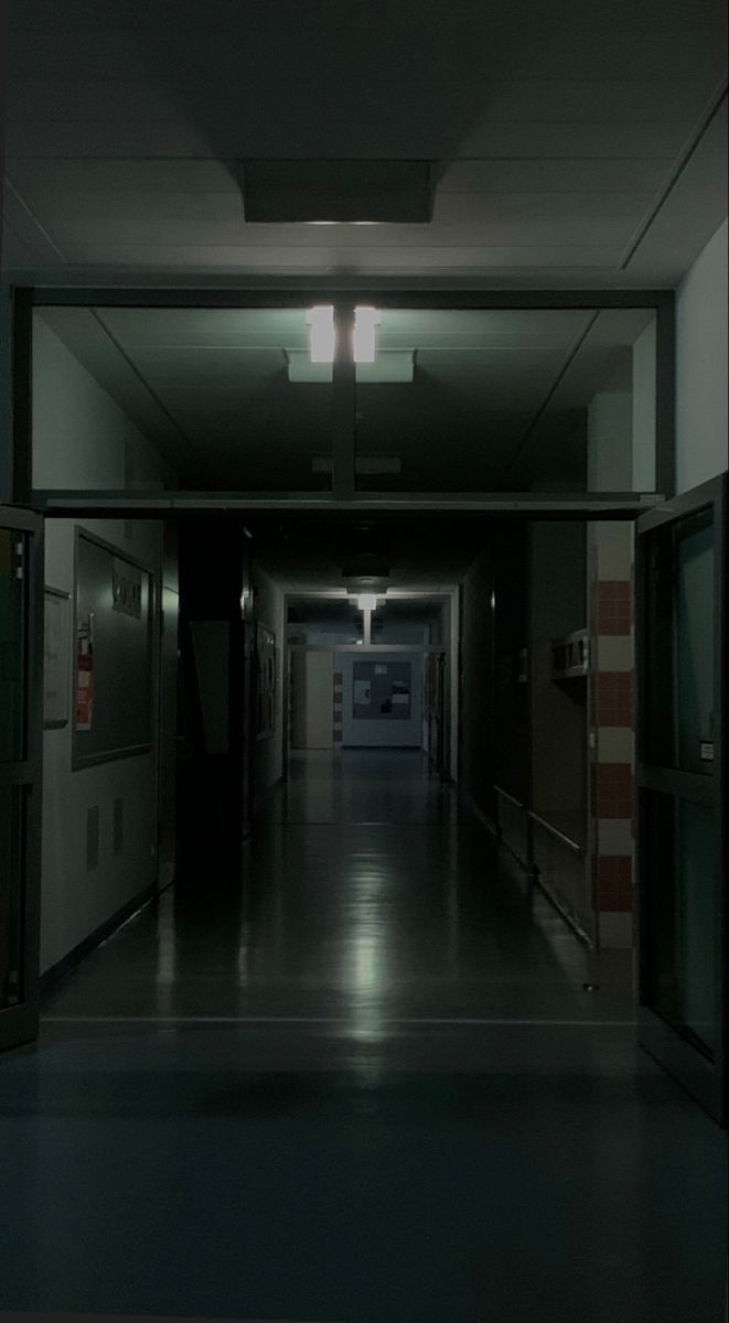 an empty hallway with lights on the ceiling and doors open to let people know where they are going