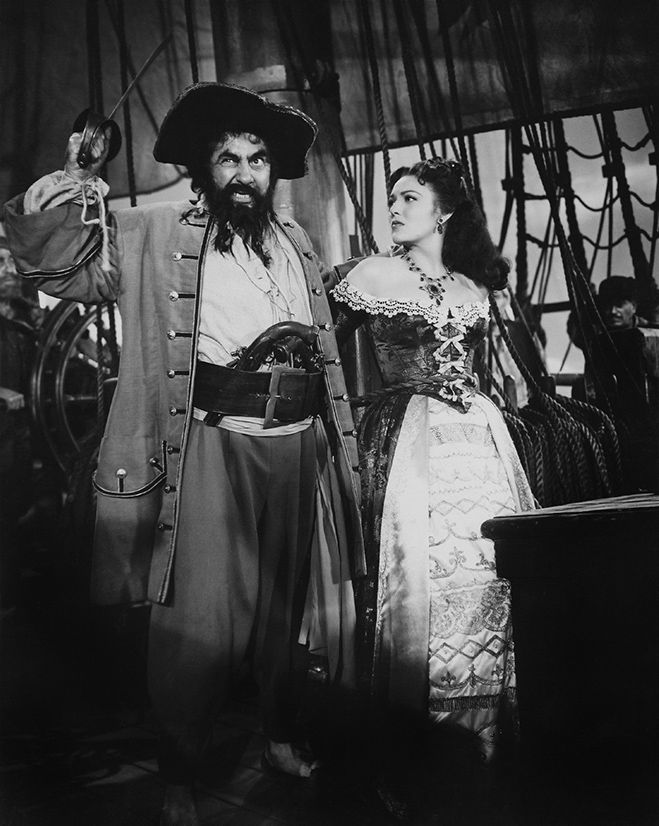 an old black and white photo of two people dressed in pirate costumes standing next to each other