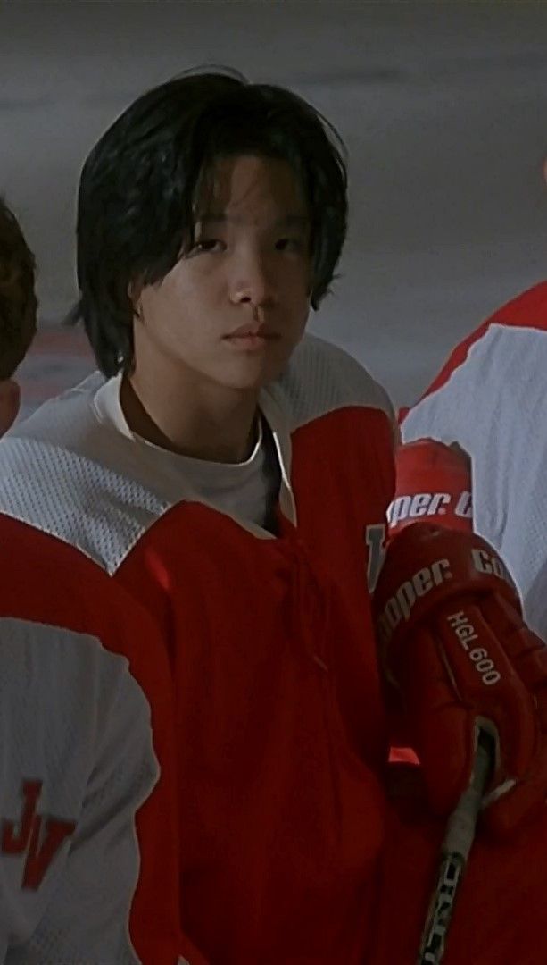 the young man is wearing a red and white hockey uniform with his hands in his pockets