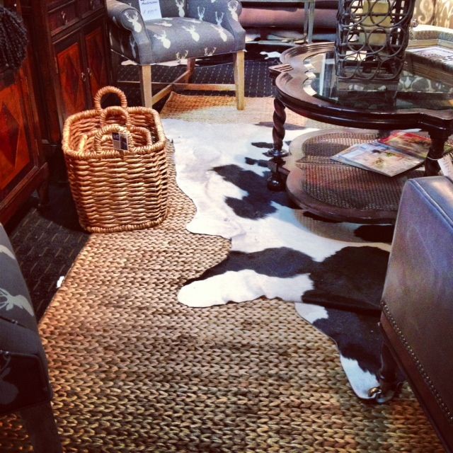 two baskets sitting on the floor in front of a chair and table with a cow hide rug