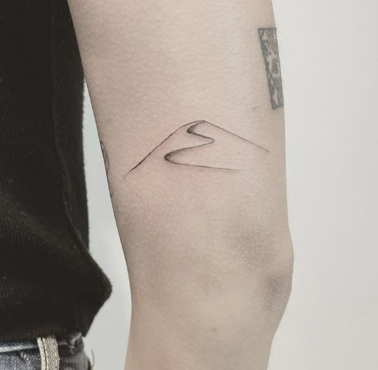 a woman's arm with a small tattoo on the left side of her arm