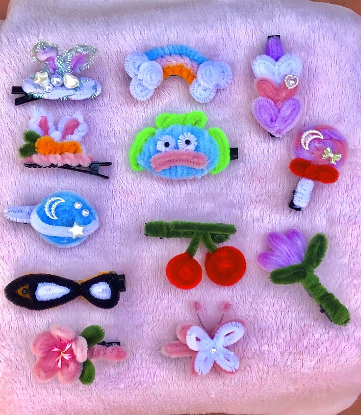 there are many different hair clips on the pink blanket with flowers and butterflies around them