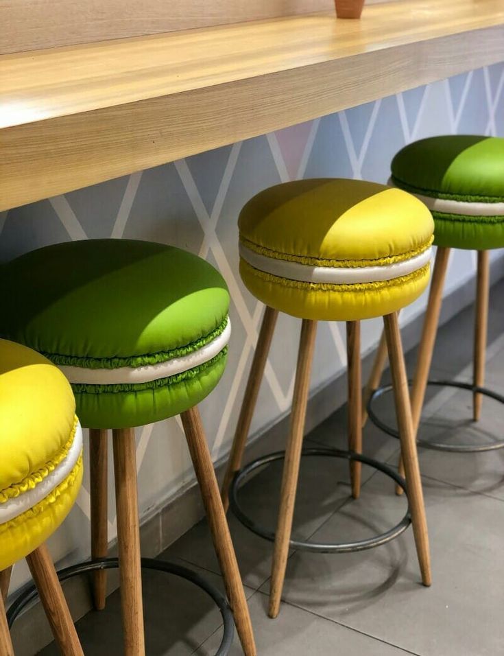 three stools with green cushions sit in front of a counter top and wallpaper