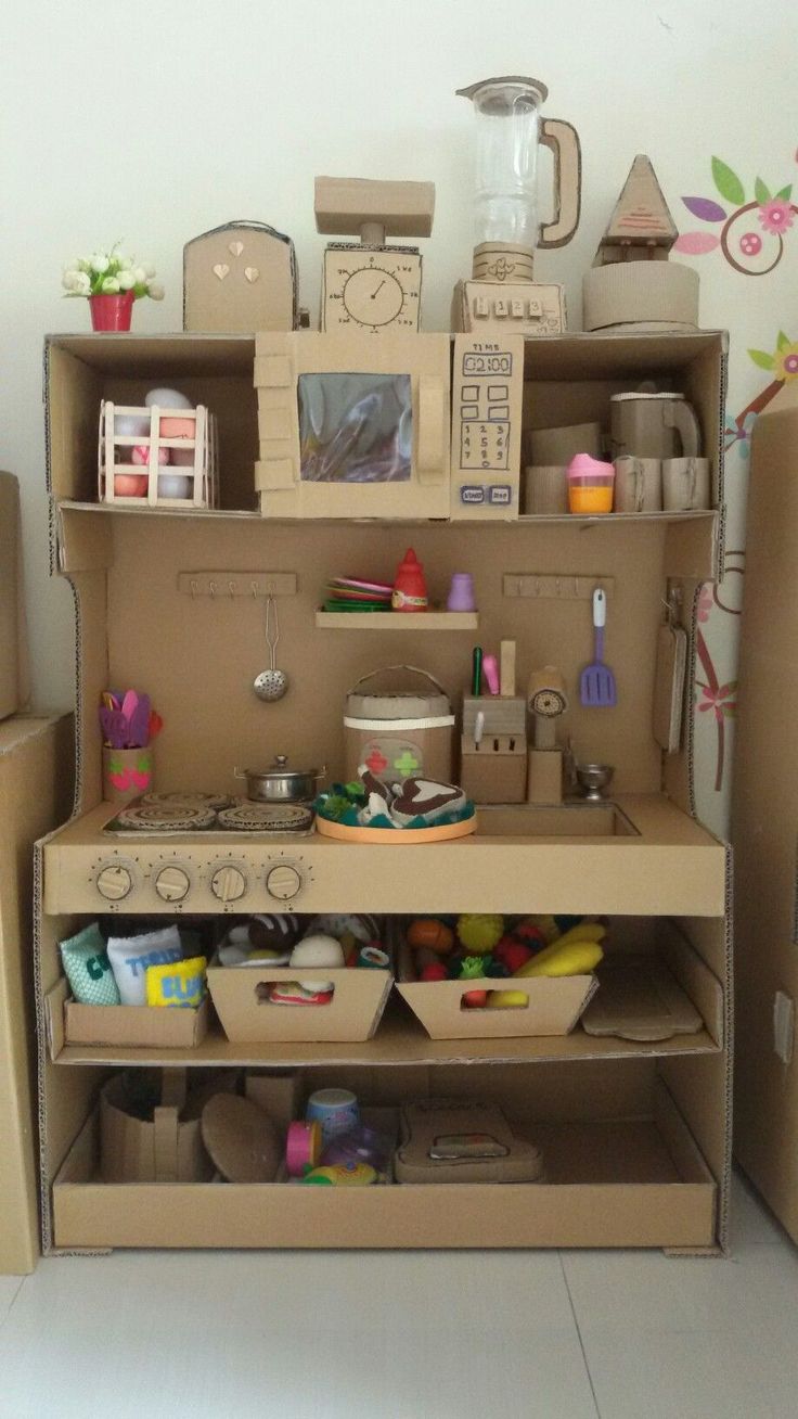 a cardboard toy kitchen with lots of items on the shelves and in front of it