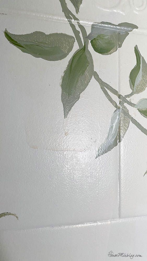 a white wall with green leaves painted on it