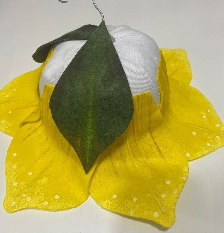 a yellow and white flower with green leaves on it's petals, hanging from a hook