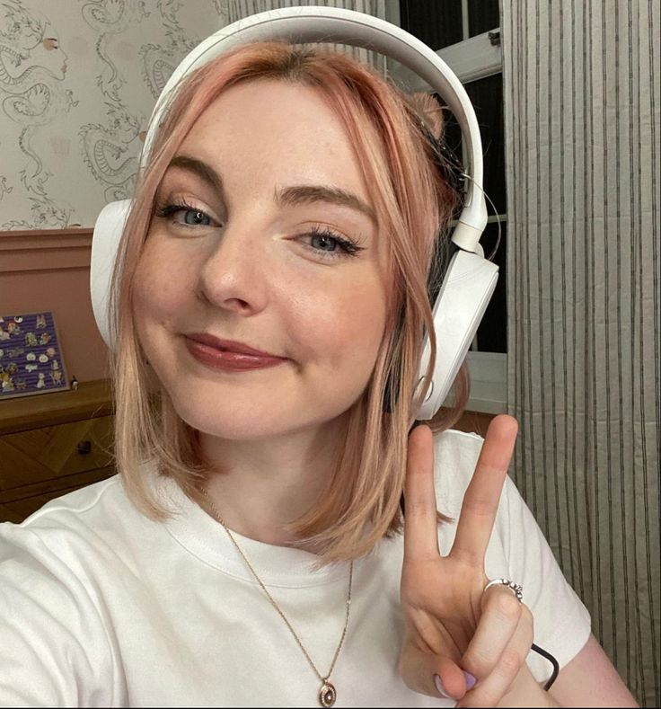 a woman wearing headphones making the peace sign