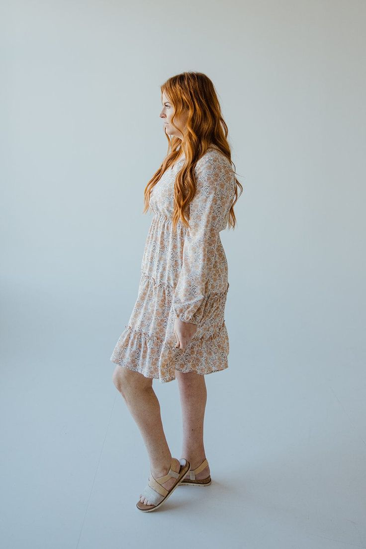 This beautiful neutral midi-length dress has all of the boho vibes! It is going to be your new go-to for date nights, weddings, and work events. This dress features a modest, shorter v-neckline and fluttery blouson long-sleeves. The blousy material flows beautifully down the dress's skirt, with the bottom featuring a tiered effect edged by ruffles. The smocked waist gives the dress an a-line fit that will accentuate your curves beautifully and provide structure to this extra flowy dress. The lin Spring Boho Knee-length Dress With Boho Print, Spring Knee-length Boho Dress, Boho Print Midi Dress For Garden Party, Bohemian Mini Dress For Garden Party In Fall, Fall Bohemian Mini Dress For Garden Party, Beige Flowy Knee-length Mini Dress, Beige Knee-length Flowy Mini Dress, Flowy Boho Print Knee-length Dress, Flowy Beige Mini Dress Knee-length