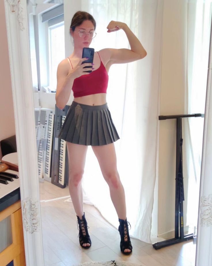 a woman taking a selfie in front of a mirror with her hand on her hip