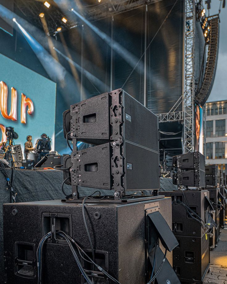 several speakers are stacked on top of each other in front of an audience at a concert