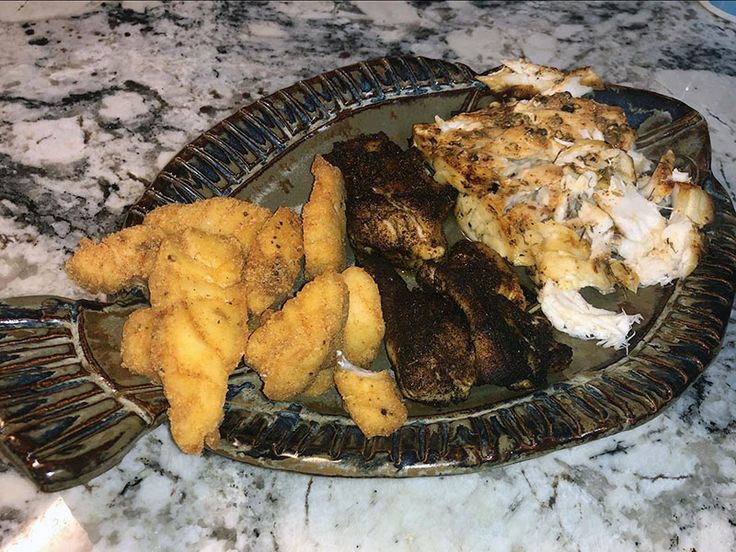 a plate full of food sitting on top of a marble counter next to a knife and fork