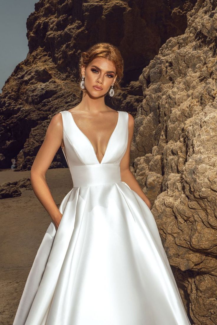 a woman in a white wedding dress standing near rocks