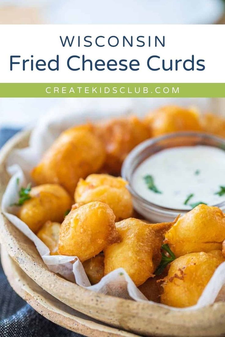 a basket filled with fried cheese curls and ranch dip in the middle, on top of a blue cloth