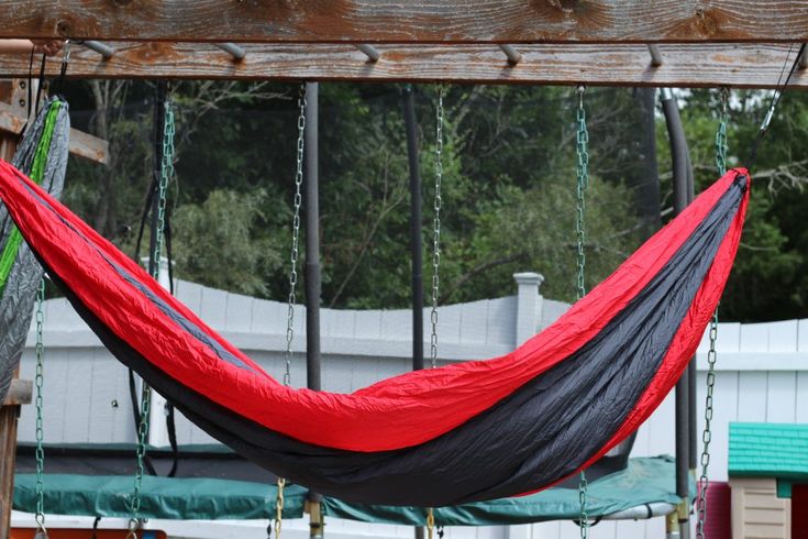 a red and black hammock hanging from a wooden structure