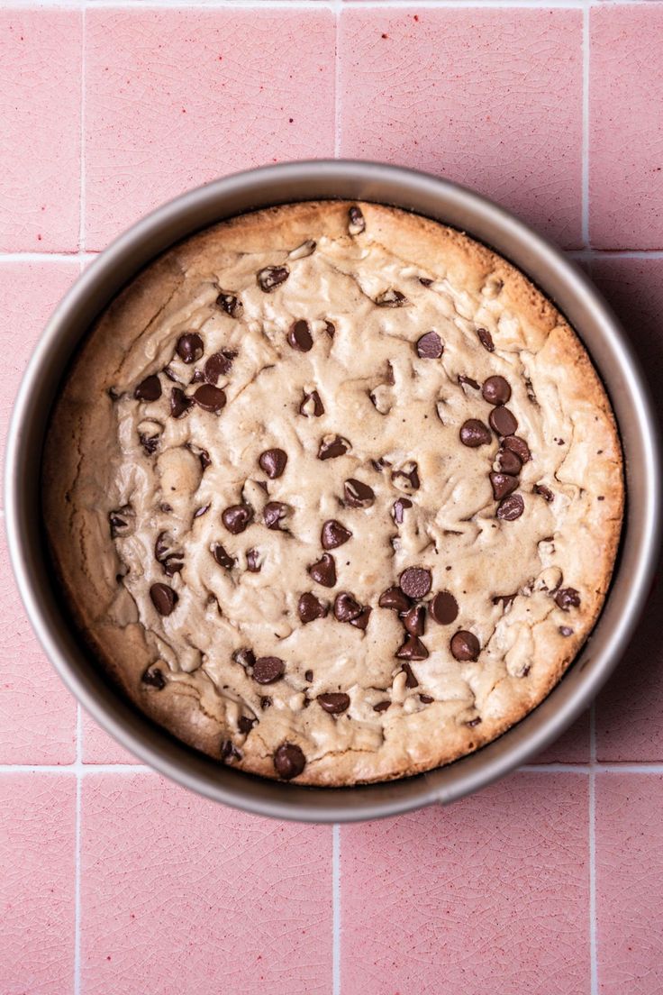 a chocolate chip cookie sitting on top of a pink tile floor