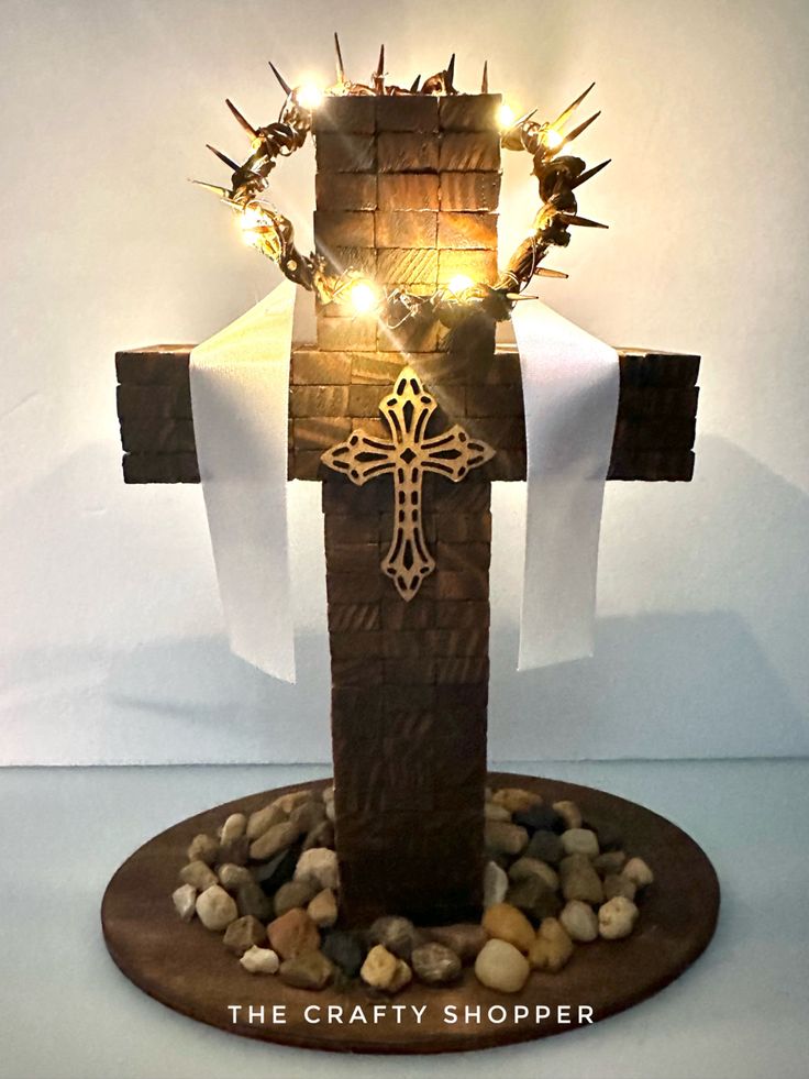 a wooden cross with lights on top of it and rocks underneath the cross is surrounded by stones