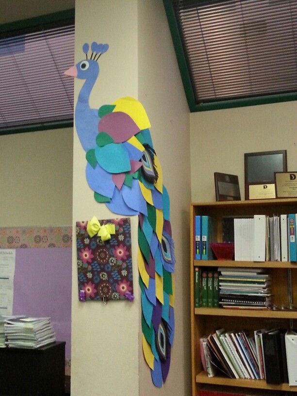 a colorful peacock is on the wall next to a bookcase and bookshelf