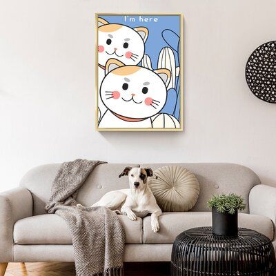 a dog is sitting on the couch in front of a cat art print hanging above it