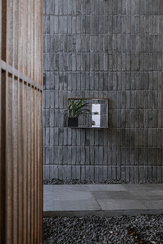 a brick wall with a mirror and plant in the middle on it's side