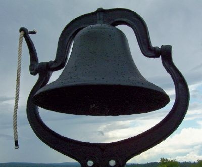 a large metal bell sitting in the middle of a field