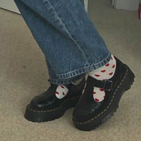 a person wearing black and white socks with red hearts on them, standing in front of a door