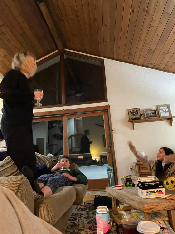 a woman standing on top of a couch in a living room next to other people