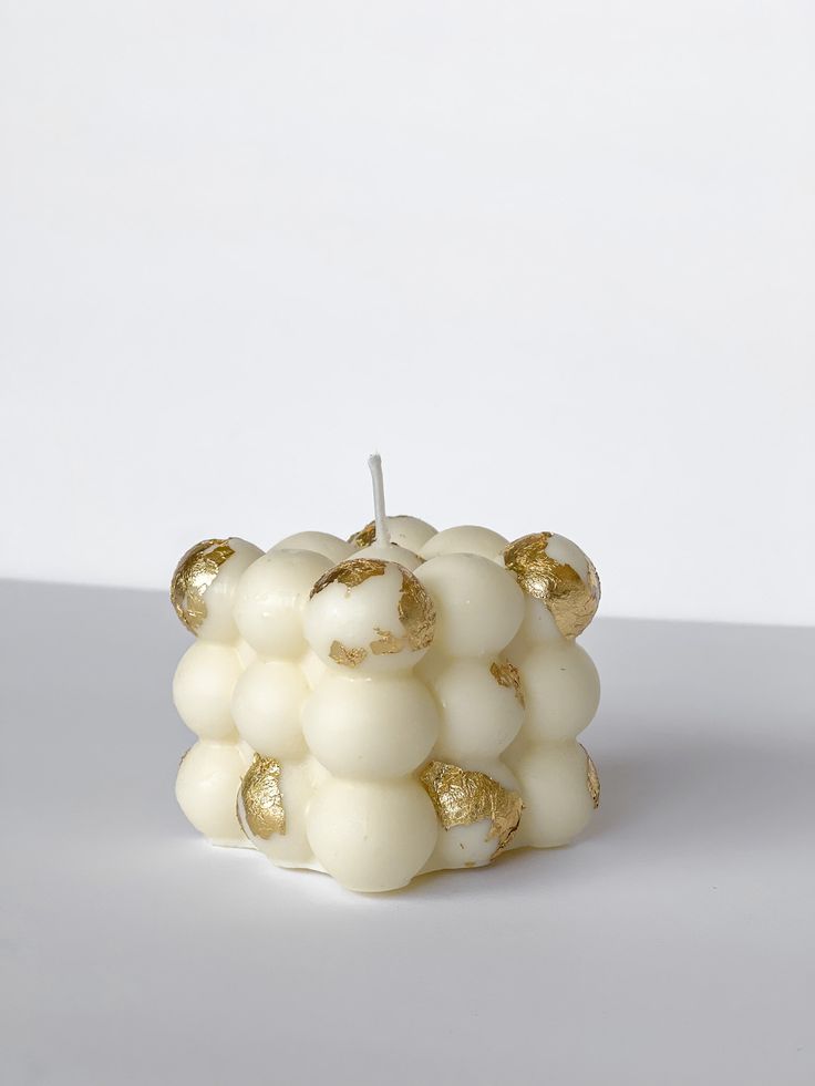 a candle that has been made out of white and gold balls on top of it