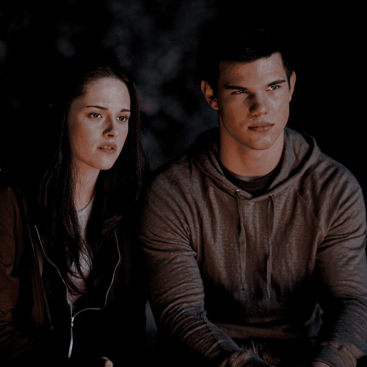 a young man and woman sitting next to each other on a bench in the dark