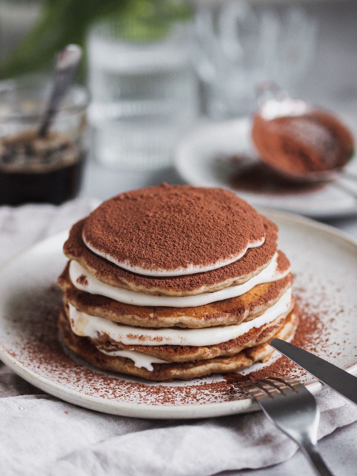 a stack of pancakes sitting on top of a white plate next to a knife and fork