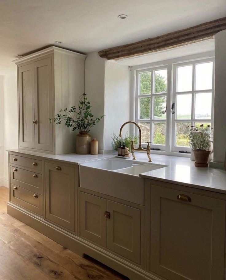 a kitchen with wooden floors and white walls, has an open window to let in natural light