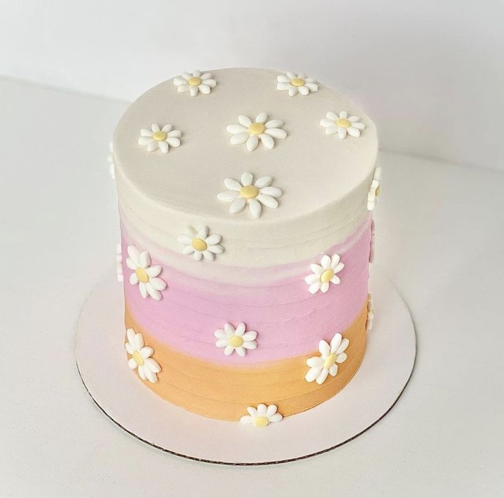 a multi layer cake with white and pink frosting flowers on the top, sitting on a plate