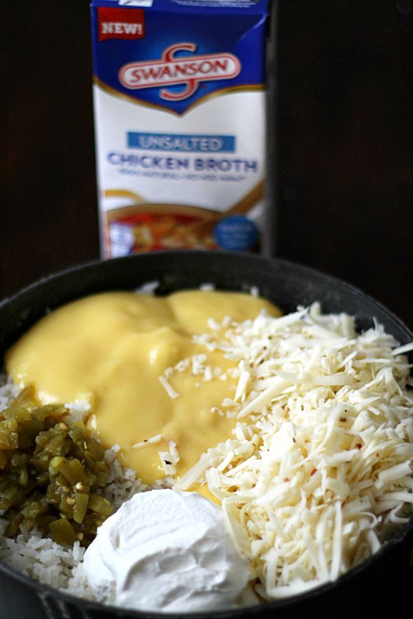 a bowl filled with rice, cheese and green beans next to a carton of gravy