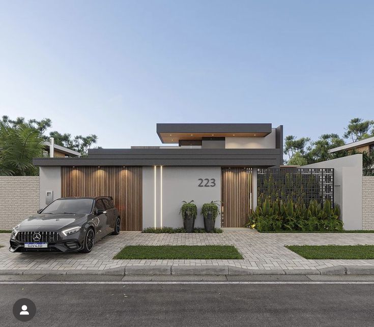 a car is parked in front of a modern house with two cars on the driveway