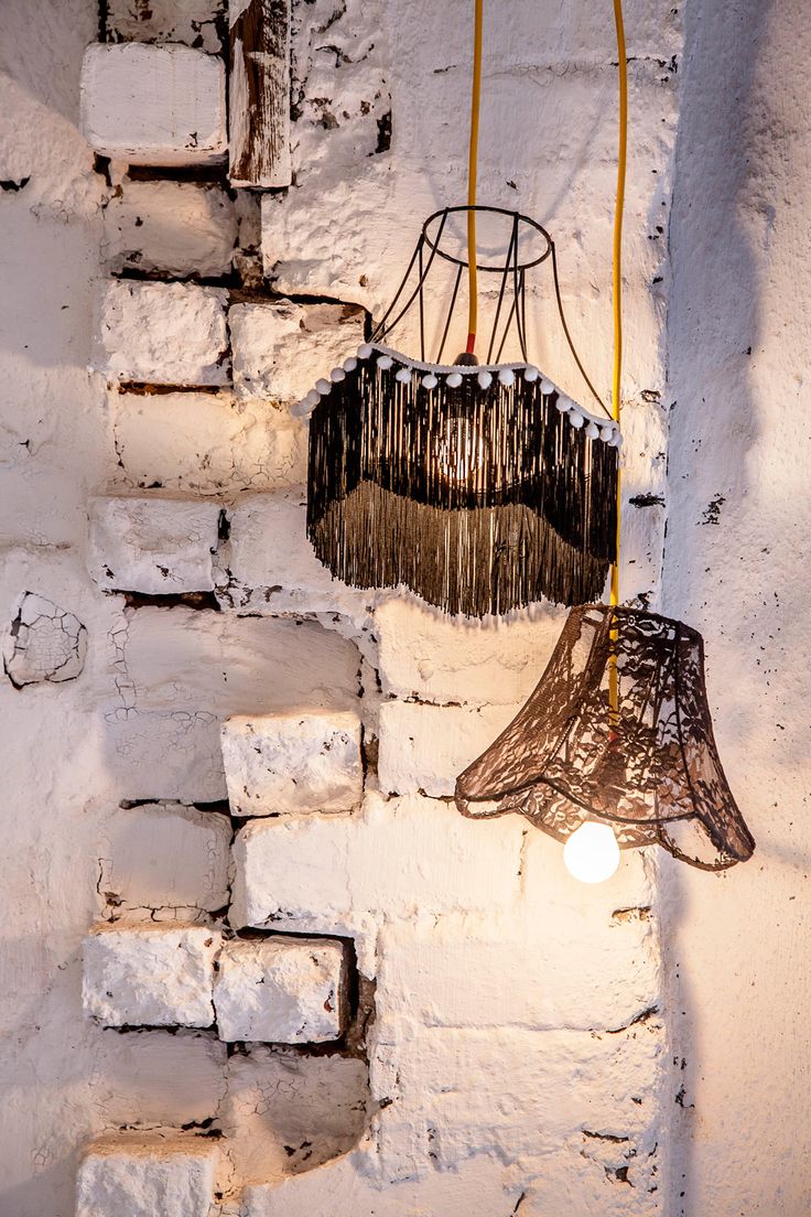 two lamps hanging from the side of a white brick wall