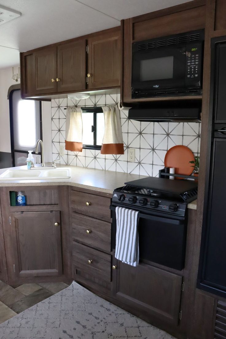 a kitchen area with stove, microwave and cabinets in an rv or trailer home setting