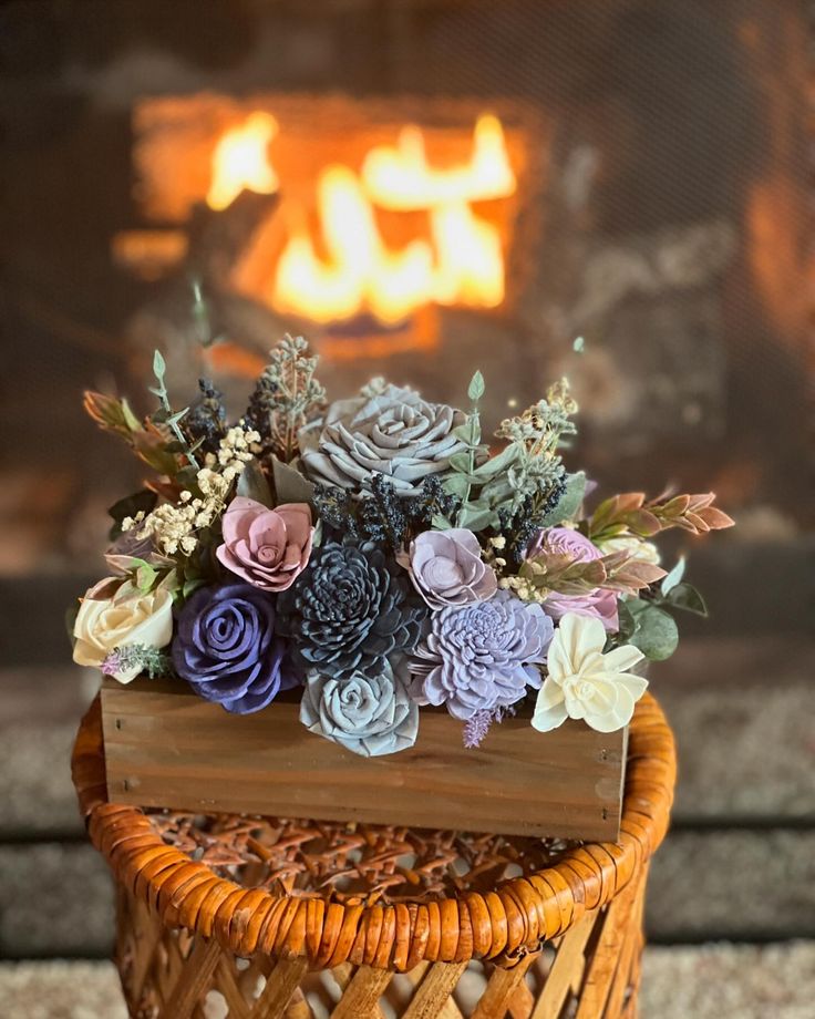 a basket with flowers sitting on top of a table next to a fire in the fireplace