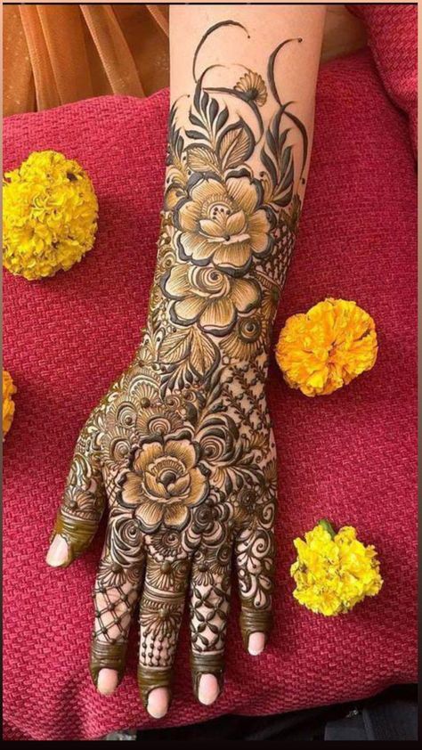 a woman's hand with henna tattoos on it and flowers around the wrist