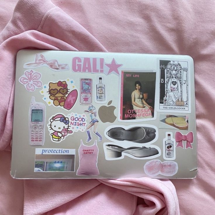 an open laptop computer sitting on top of a pink blanket covered in stickers and decals