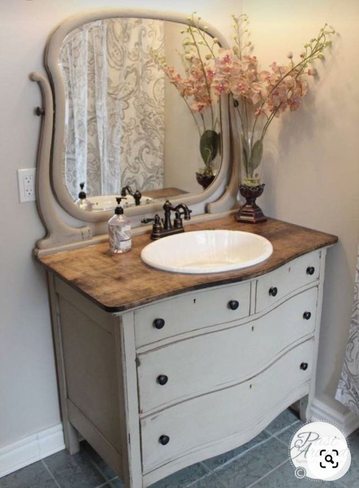 a bathroom vanity with a large mirror above it and flowers in vases on the counter