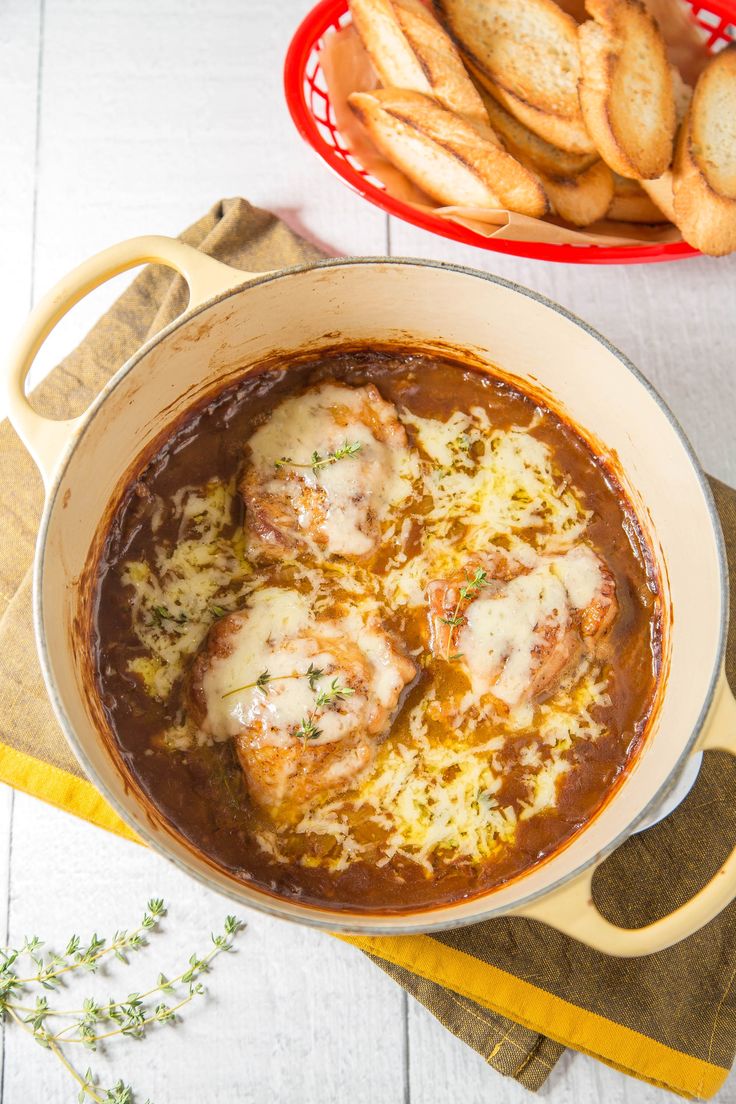 a bowl of meat and cheese soup with bread on the side