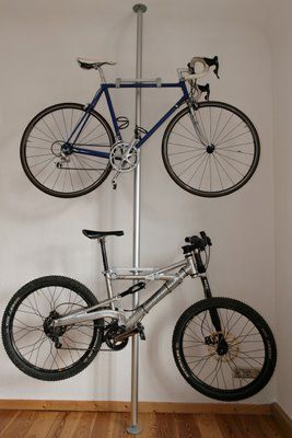 a bike mounted to the side of a pole on top of a wooden floor next to a white wall