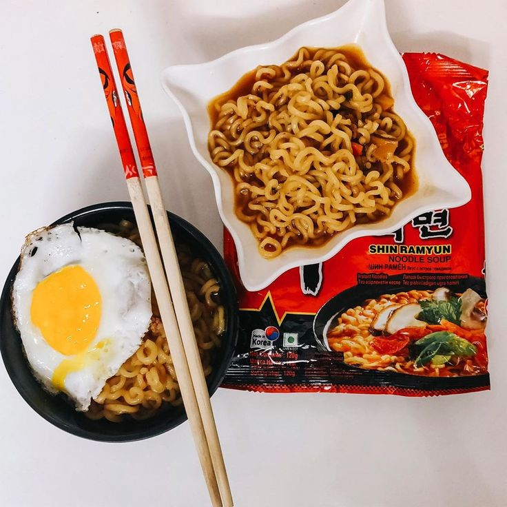 noodles, eggs and chopsticks are sitting on a table next to a bag of ramen