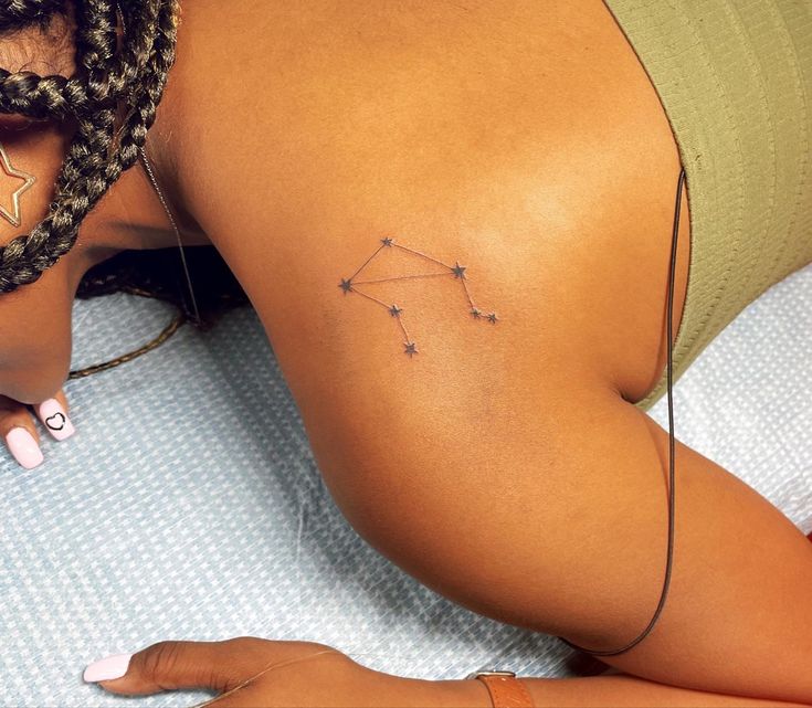 a woman laying on top of a bed next to her stomach with tattoos on it