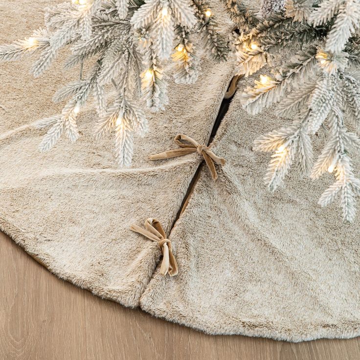 a close up of a christmas tree with lights on it's branches and some bows