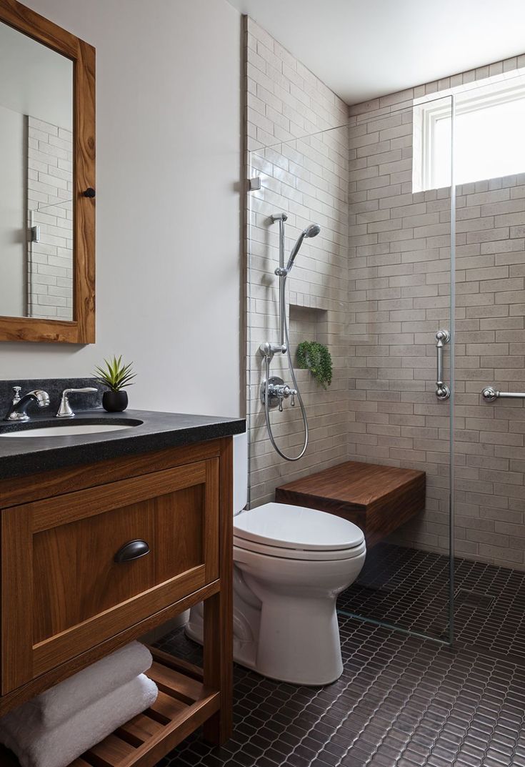 a white toilet sitting next to a walk in shower under a bathroom mirror above a sink