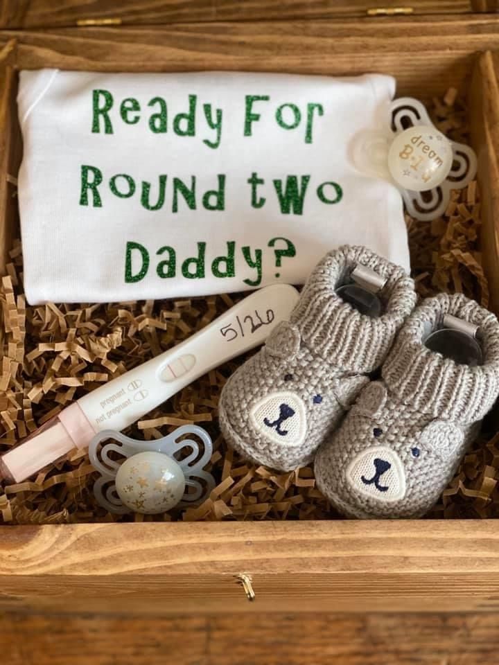 a box with baby items in it and a sign that says ready for round two daddy